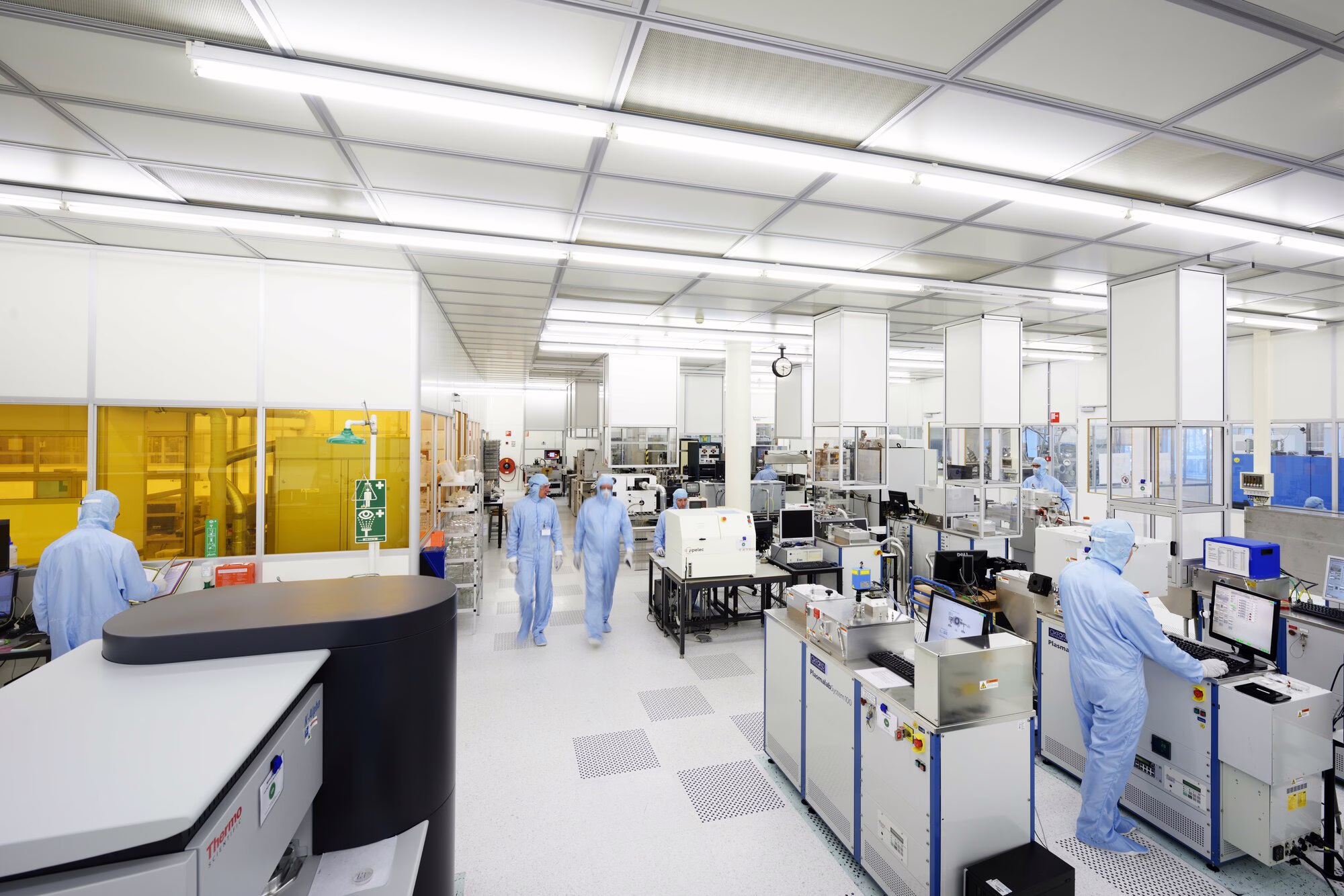 Moderne laboratoriumruimte met werkstations, apparatuur en medewerkers in blauwe labjassen